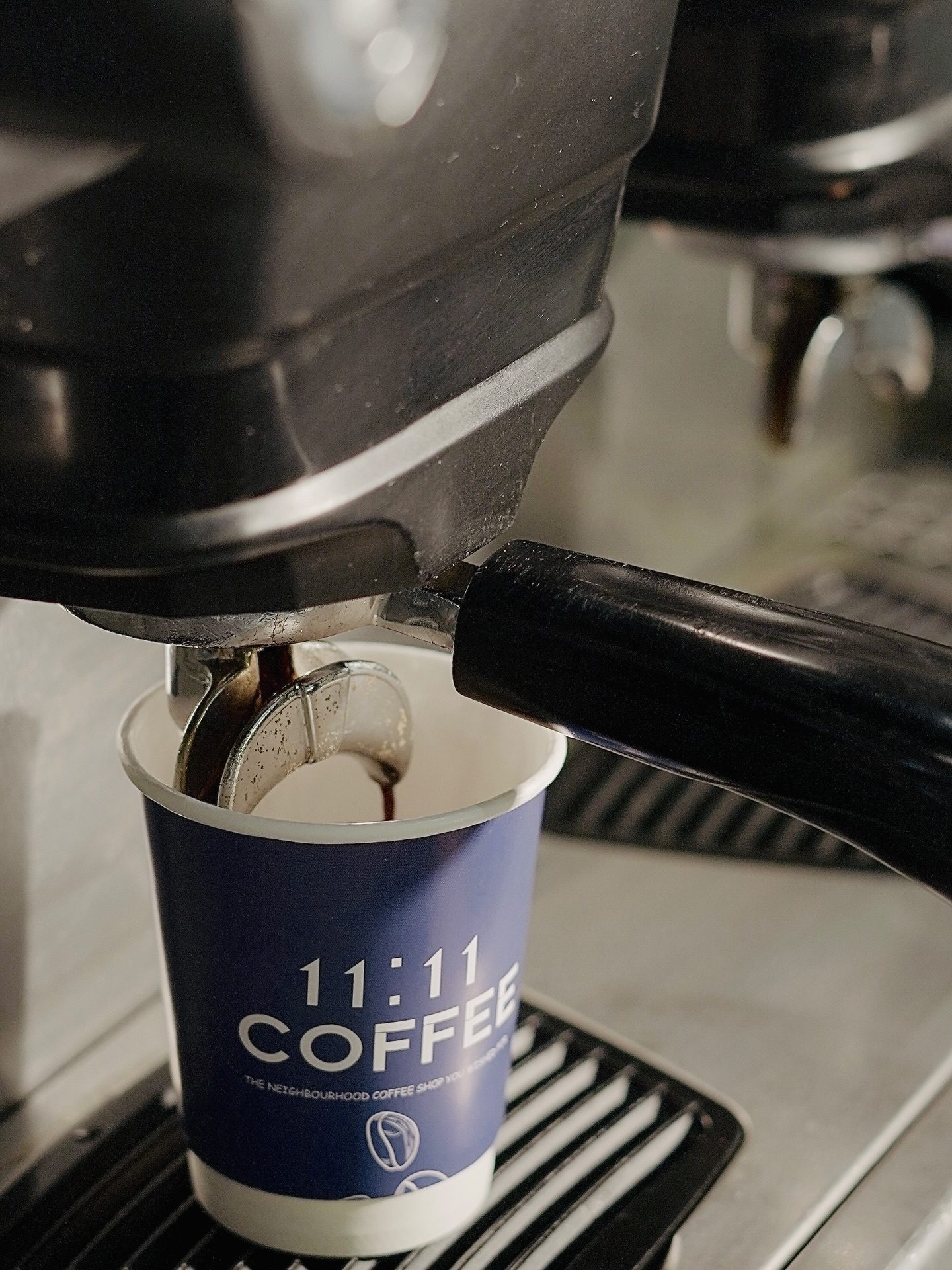 Espresso pouring into a branded 11:11 Coffee cup